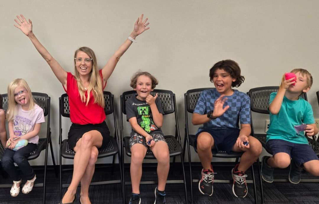 Lucie Trubak leading a Life Skills Labs class for kids in New Braunfels, arms raised, as children sit in chairs
