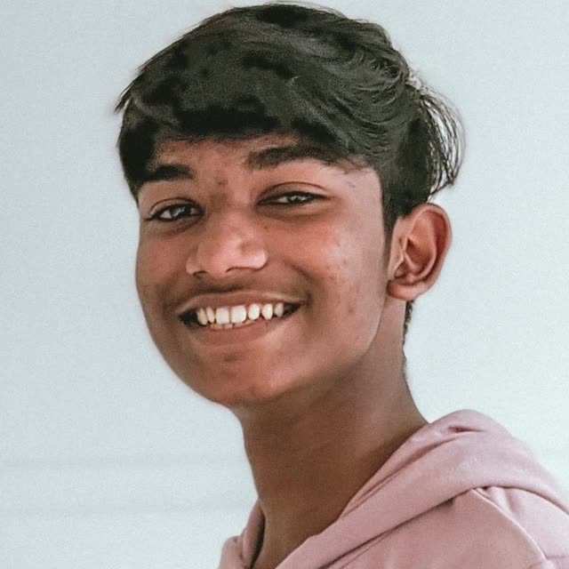 A smiling boy in a pink and white hoodie in a head-and-shoulders portrait