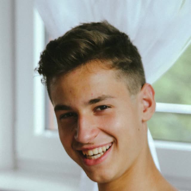 A smiling boy in a white t-shirt in a head-and-shoulders portrait