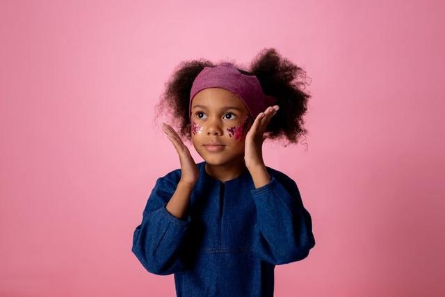 A girl with face paint, hands on her cheeks