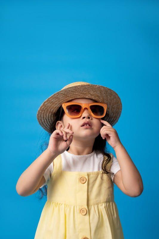 A child wearing a straw hat and orange sunglasses