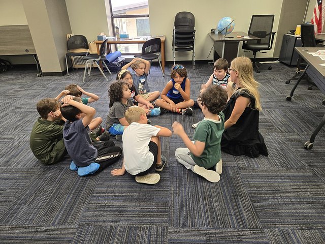 An instructor and children seated in a circle with a ball during a Life Skills Labs class