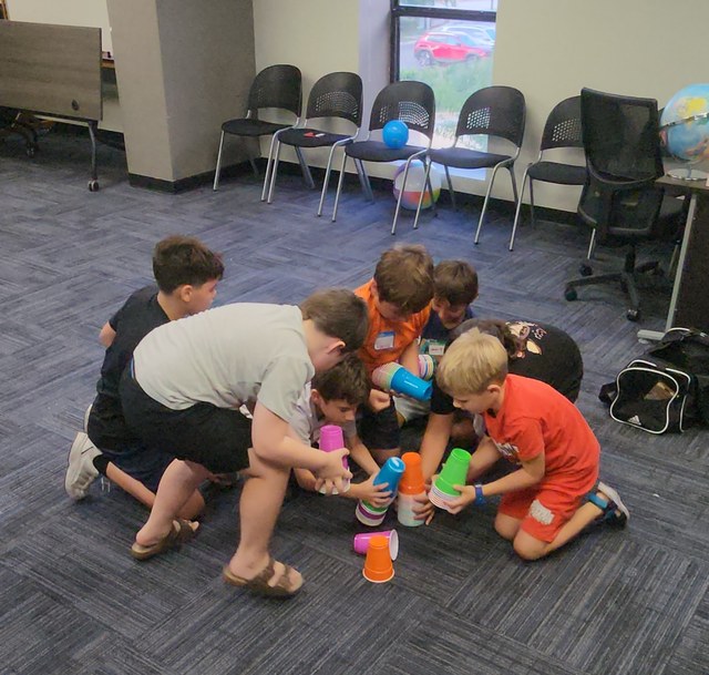 Children stacking colorful cups together on the floor during a Life Skills Labs class